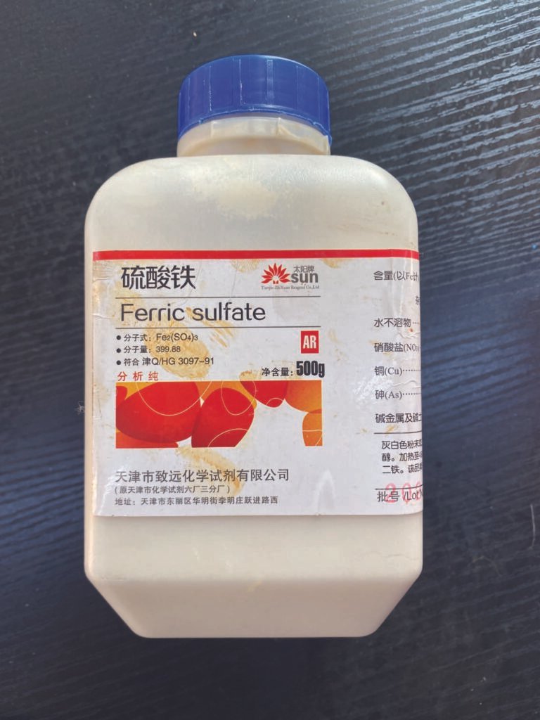Bottle of ferric sulfate used as a pigment and oxidizing agent in the artist’s experimental painting process.
